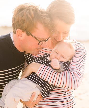 Family hugging on the beach at sunrise during a photo session