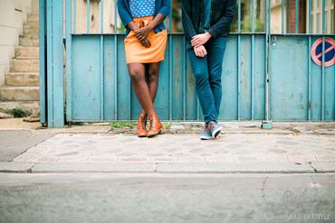 Couple devant un portail avec jambes croisées, dans le XXè à Paris