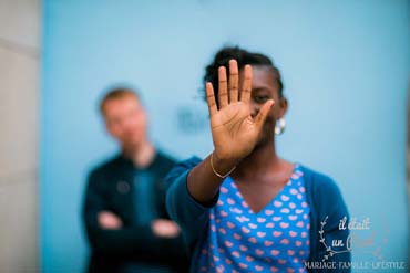 Couple devant un mur bleu à Paris pendant leur séance engagement