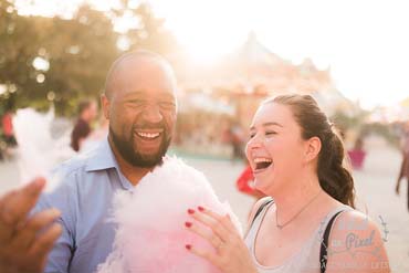 Couple riant en mangeant de la barbe à papa lors d'une fête foraine au jardin des tuileries à Paris