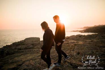 Couple marchant sur une falaise rocheuse au dessus de l'océan aux Sables d'Olonne au coucher du soleil
