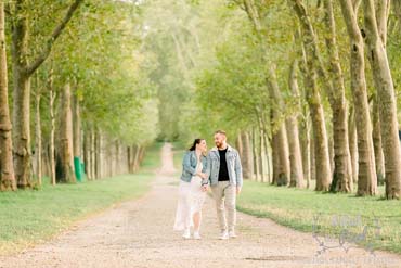 Couple marchant dans une longue allée d'arbres à Versailles