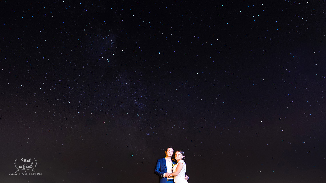 Photo de nuit d'un couple de mariés sous les étoiles