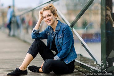 Portrait d'une jeune femme assise sur le Pont des Arts à Paris tout près du Louvre 