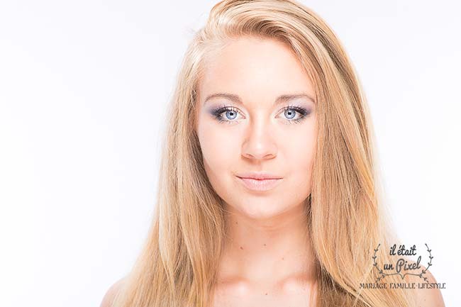 Portrait high key lumineux sur fond blanc d'une jeune mannequin blonde pendant un shooting photo beauté en studio