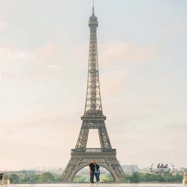 Photo d'un couple américain au lever du soleil devant la Tour Eiffel à Paris