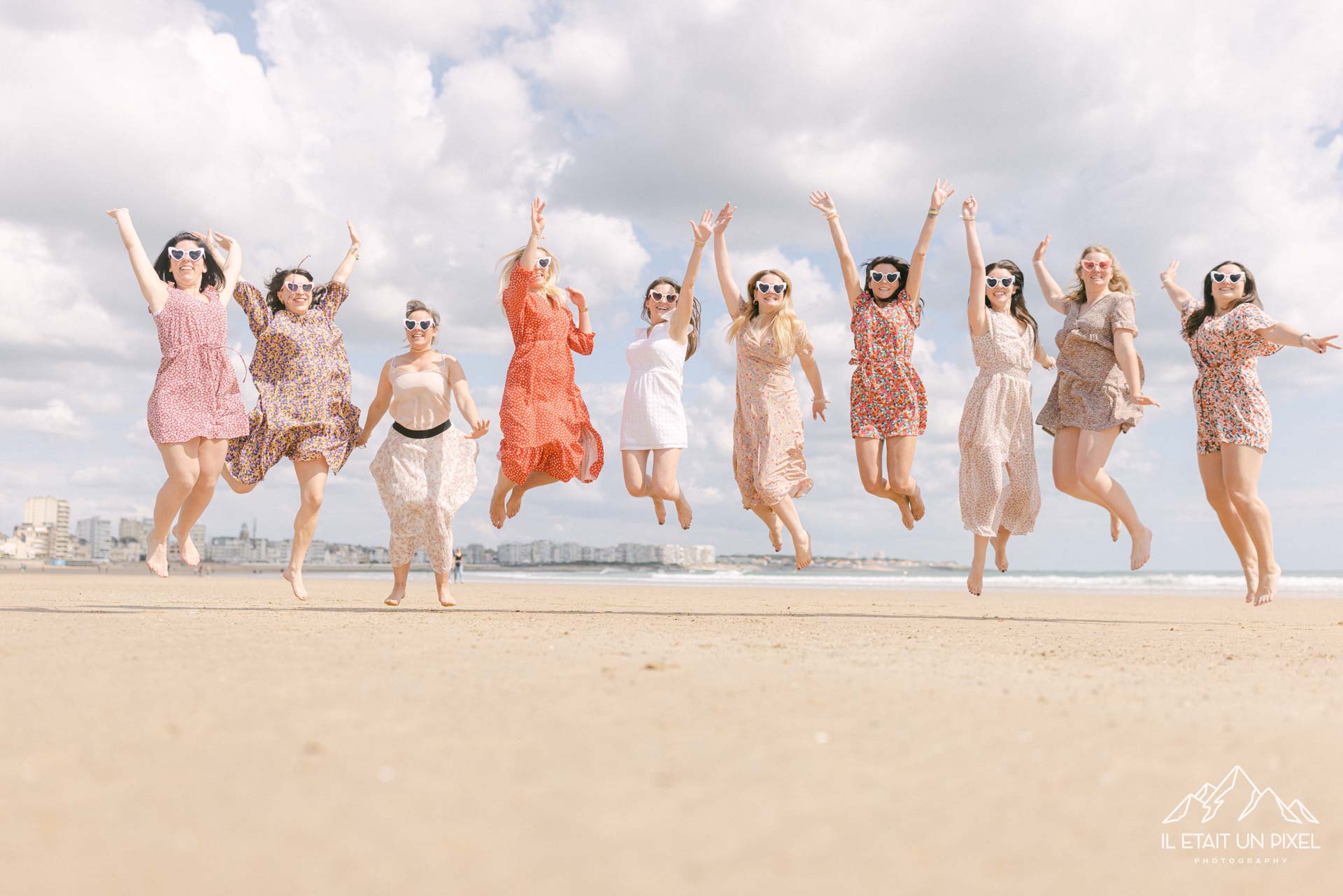 Groupe de filles sautant en l'air sur la plage pendant leur séance enterrement de vie de jeune fille