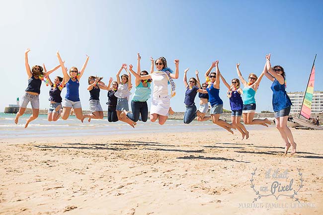 Photo de groupe lors d'un shooting EVJF sur la plage aux Sables d'Olonne avec les participantes sautant en l'air et s'amusant