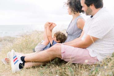 Photo de famille lifestyle sur laquelle le fils joue avec ses jambes sur ses parents