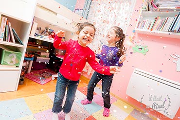 Photo prise sur le vif d'enfants sautant dans leur chambre sous une pluie de confettis 