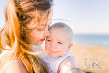 Photo prise sur le vif d'un bébé avec sa maman cheveux aux vents près de la baie de Cayola aux Sables d'Olonne
