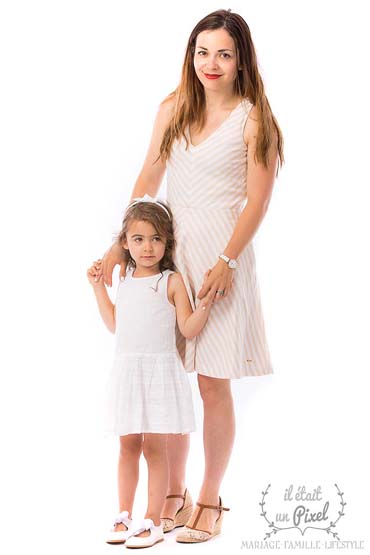 Photo de famille en studio d'une jeune mère en pieds avec sa fille portant des robes claires 