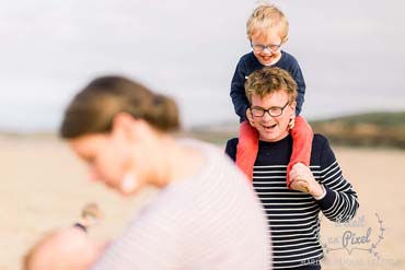 Famille avec enfants pendant un shooting lifestyle sur la plage en Vendée avec un des enfants sur les épaules de son père