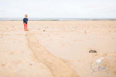Photo de famille lifestyle avec un enfant jouant avec un rateau sur la plage aux Sables d'Olonne en Vendée