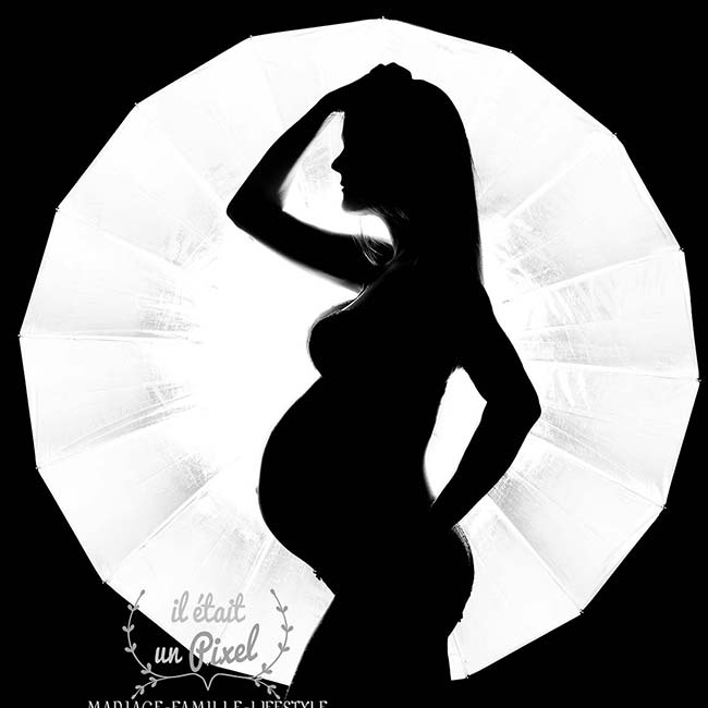 Photo Noir et Blanc en silouhette d'une femme enceinte de profil devant un cercle de lumiere blanc