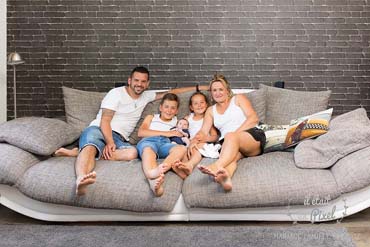 Photo lifestyle à domicile d'un bébé avec sa famille sur canapé lors d'un shooting naissance