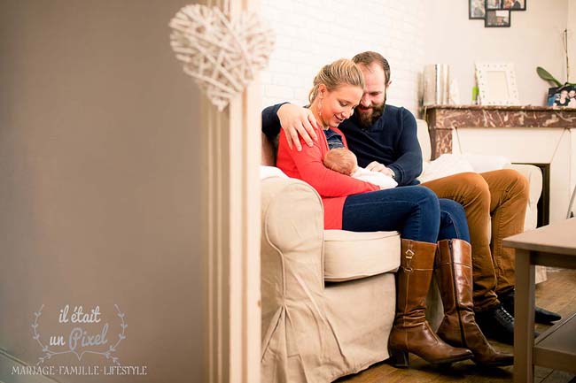 Photo lifestyle à domicile d'un bébé avec ses parents lors d'un shooting naissance