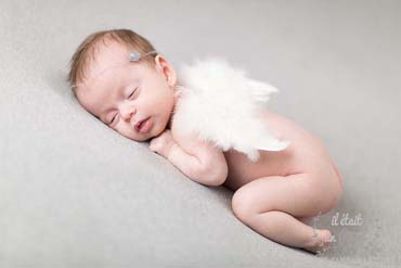 Photo d'un bébé en pose tushy up et avec des ailes lors d'un shooting naissance type newborn posing en studio