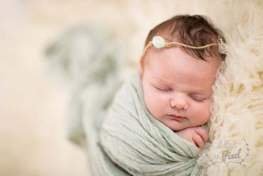Photo d'un bébé enveloppé et sur flokati lors d'un shooting naissance type newborn posing en studio